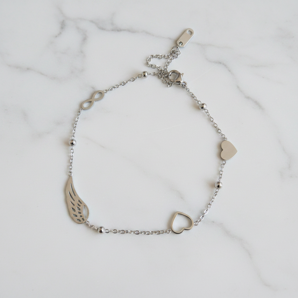 Bracelet argenté cœur et aile sur marbre blanc