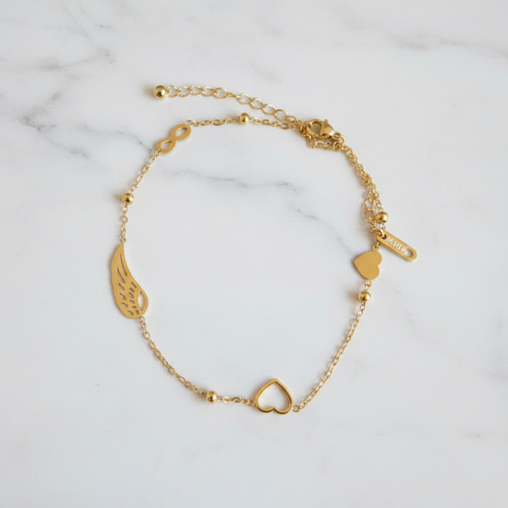 Bracelet doré cœur et aile sur marbre blanc