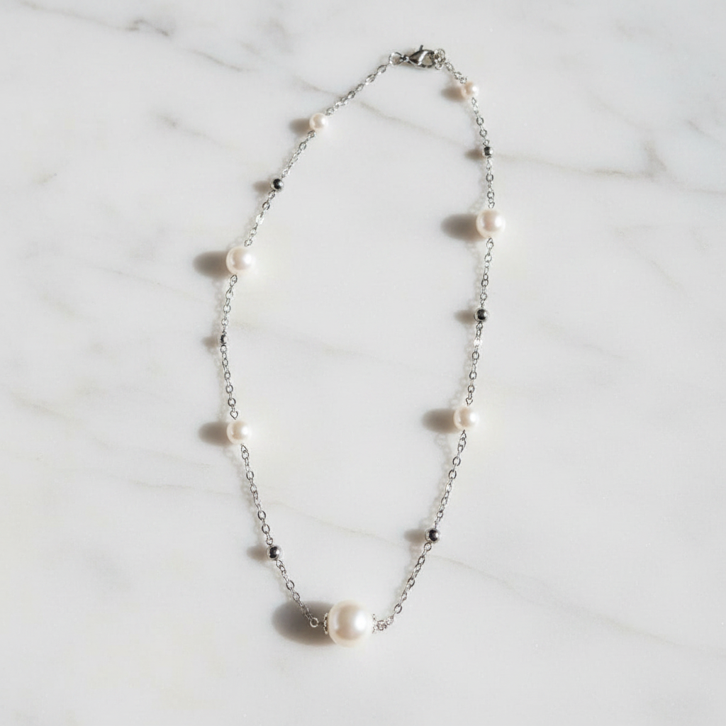 Collier argenté perles nacrées sur marbre blanc